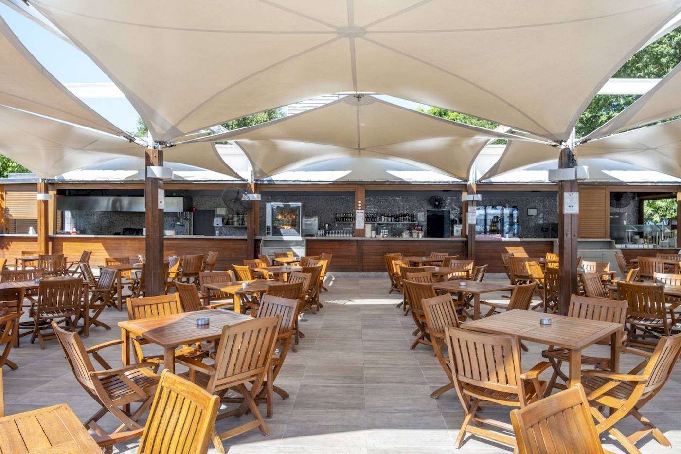Terrasse des Side Star Elegance Hotels mit vielen Holztischen und Stühlen unter großen Sonnensegeln.