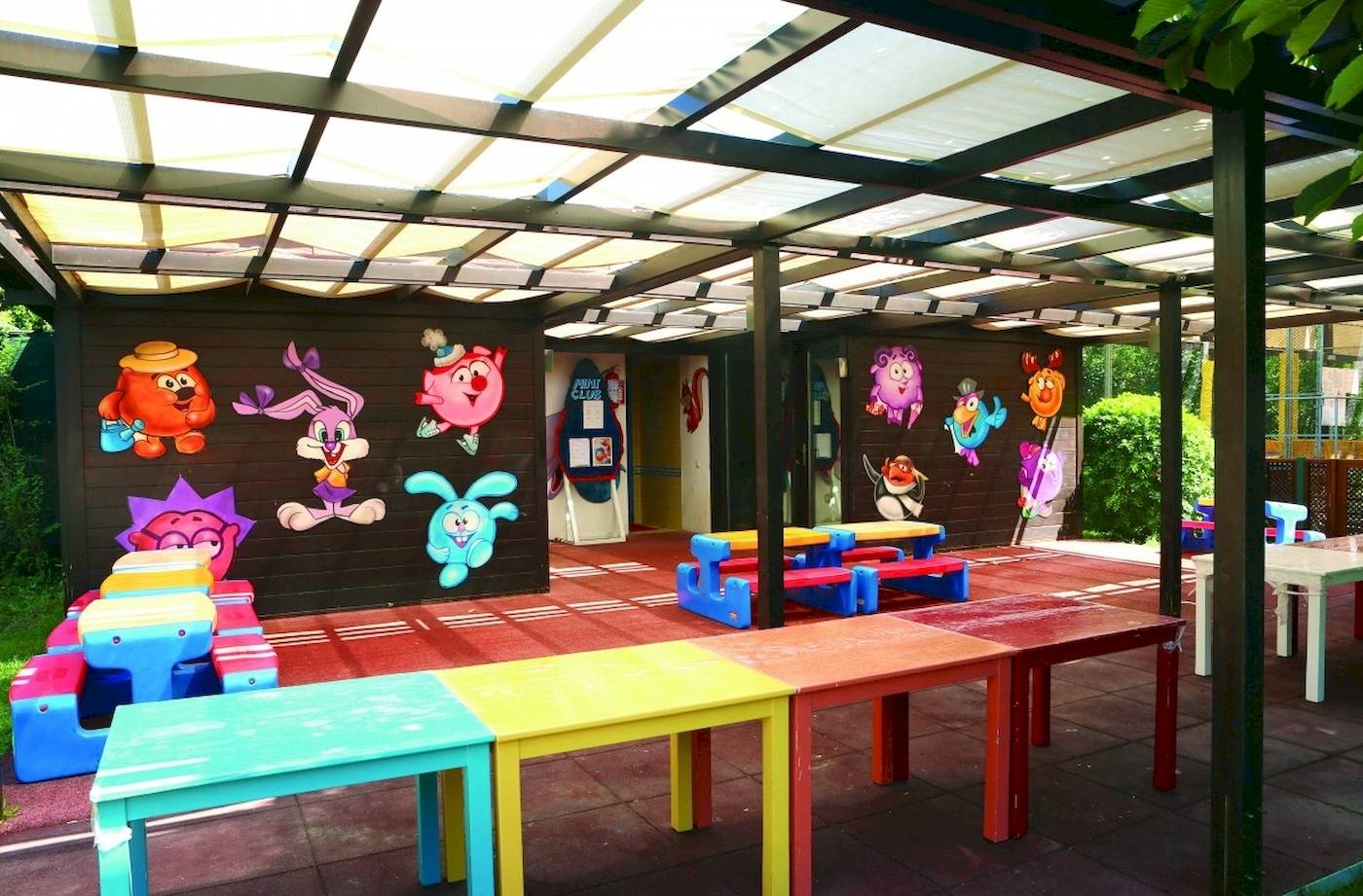 Spielbereich für Kinder unter einer Überdachung im Hotel Side Star Elegance mit bunten Tischen und Stühlen.