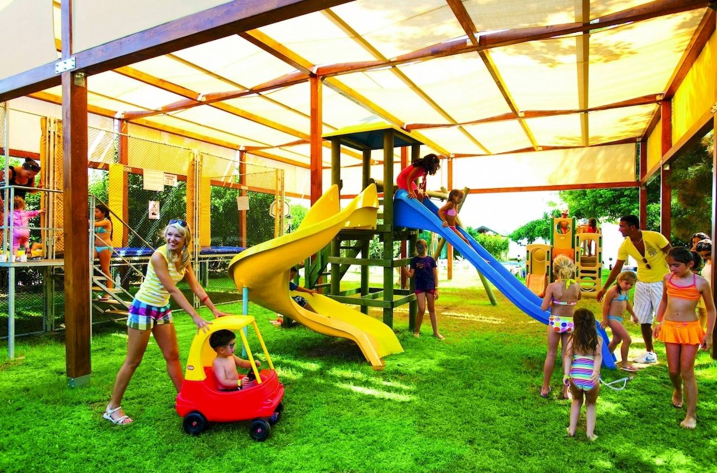 Kinder spielen auf einem Spielplatz im Freien im Hotel Side Star Elegance, mit Rutschen und einem Auto.
