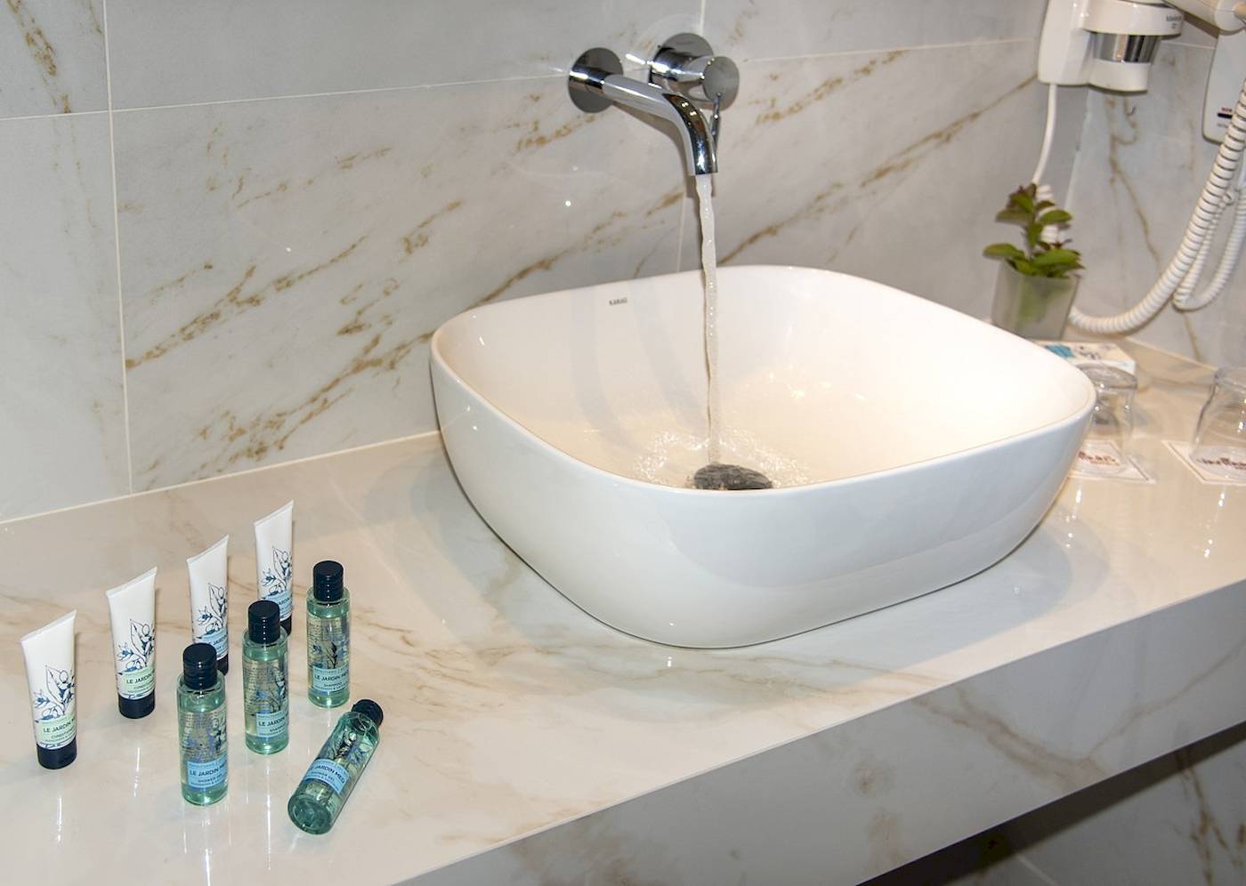Waschbecken im Badezimmer des Vantaris Luxury Beach Resorts mit Wasserhahn und Pflegeprodukten.