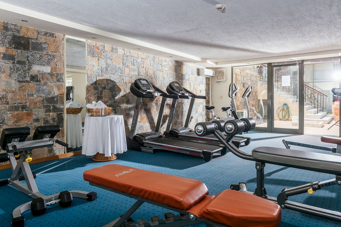 Fitnessraum im Arina Beach Resort mit Laufbändern, Hantelbank und Hanteln.