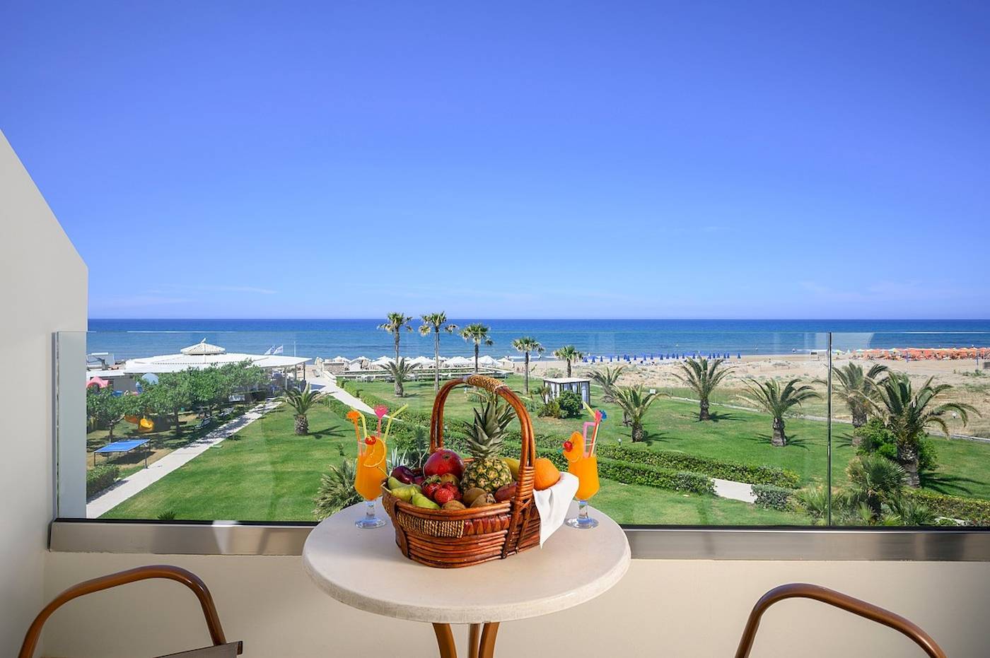 Blick aus dem Hotelfenster auf einen Strand und ein Meer mit einer Glaswand.