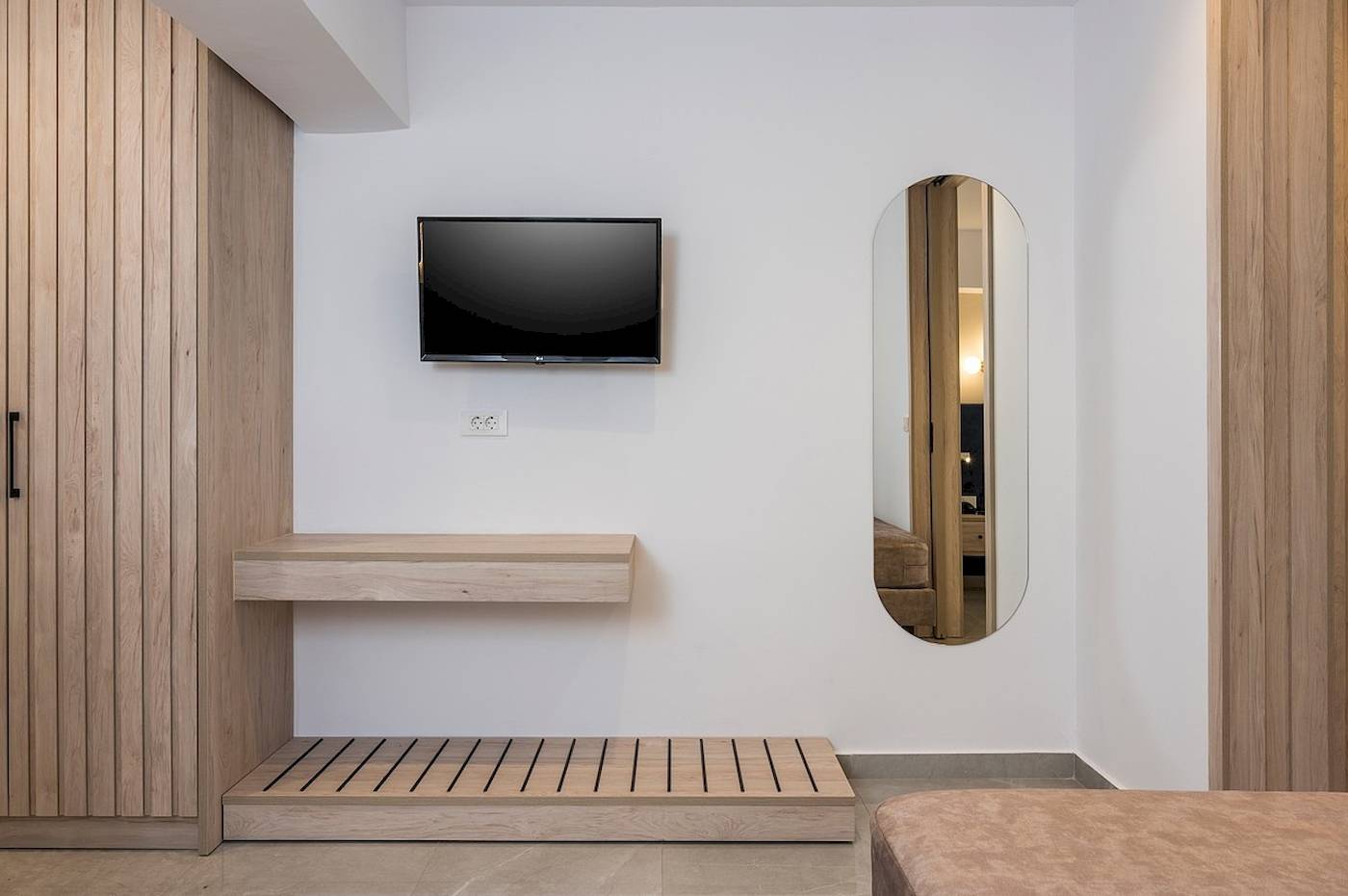 Innenansicht eines Zimmers im Vantaris Palace Hotel mit einer Wand, einem Fernseher und einem Spiegel.