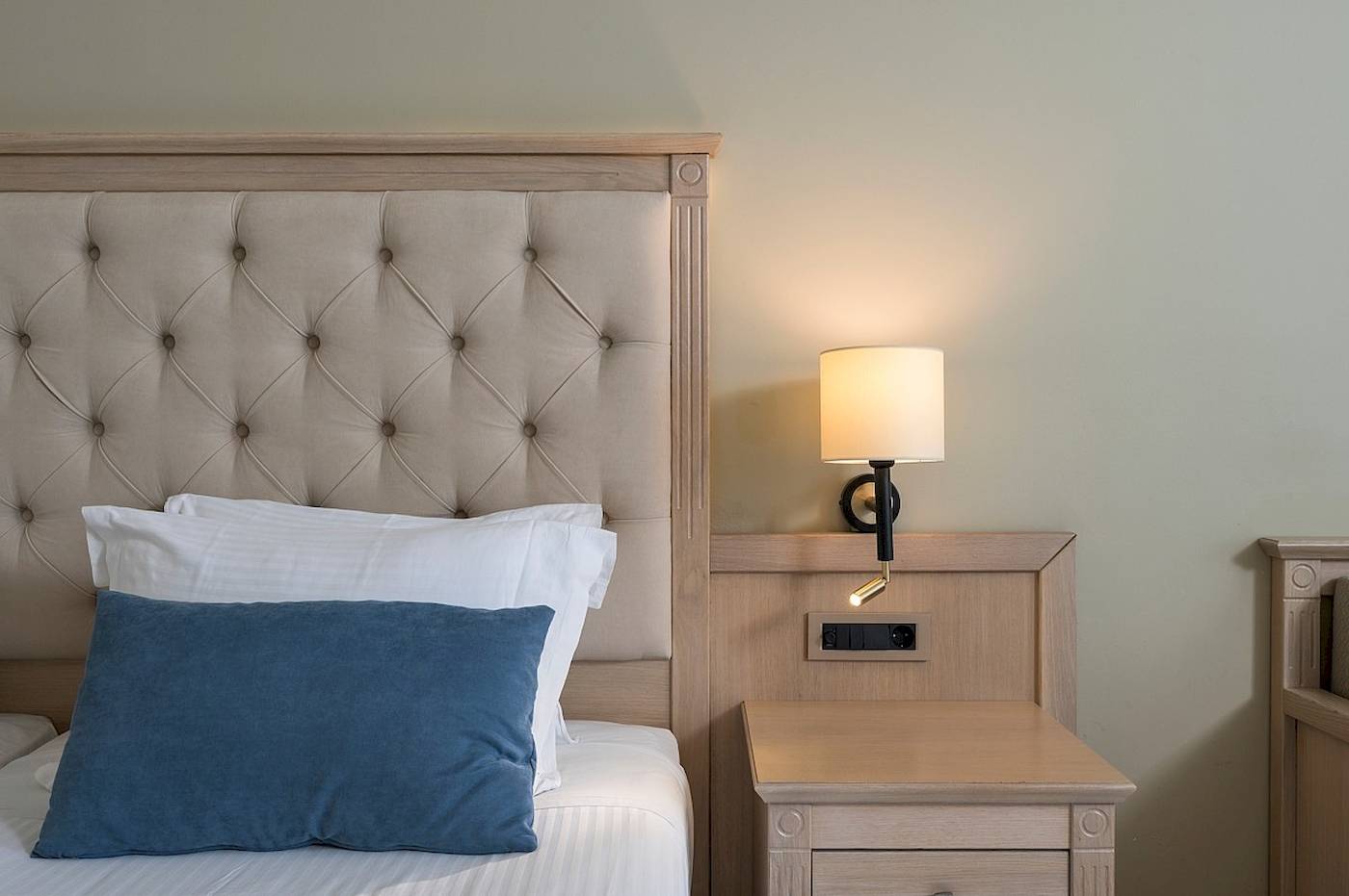 Bett im Vantaris Palace Hotel mit Kissen und Nachttisch neben dem Bett