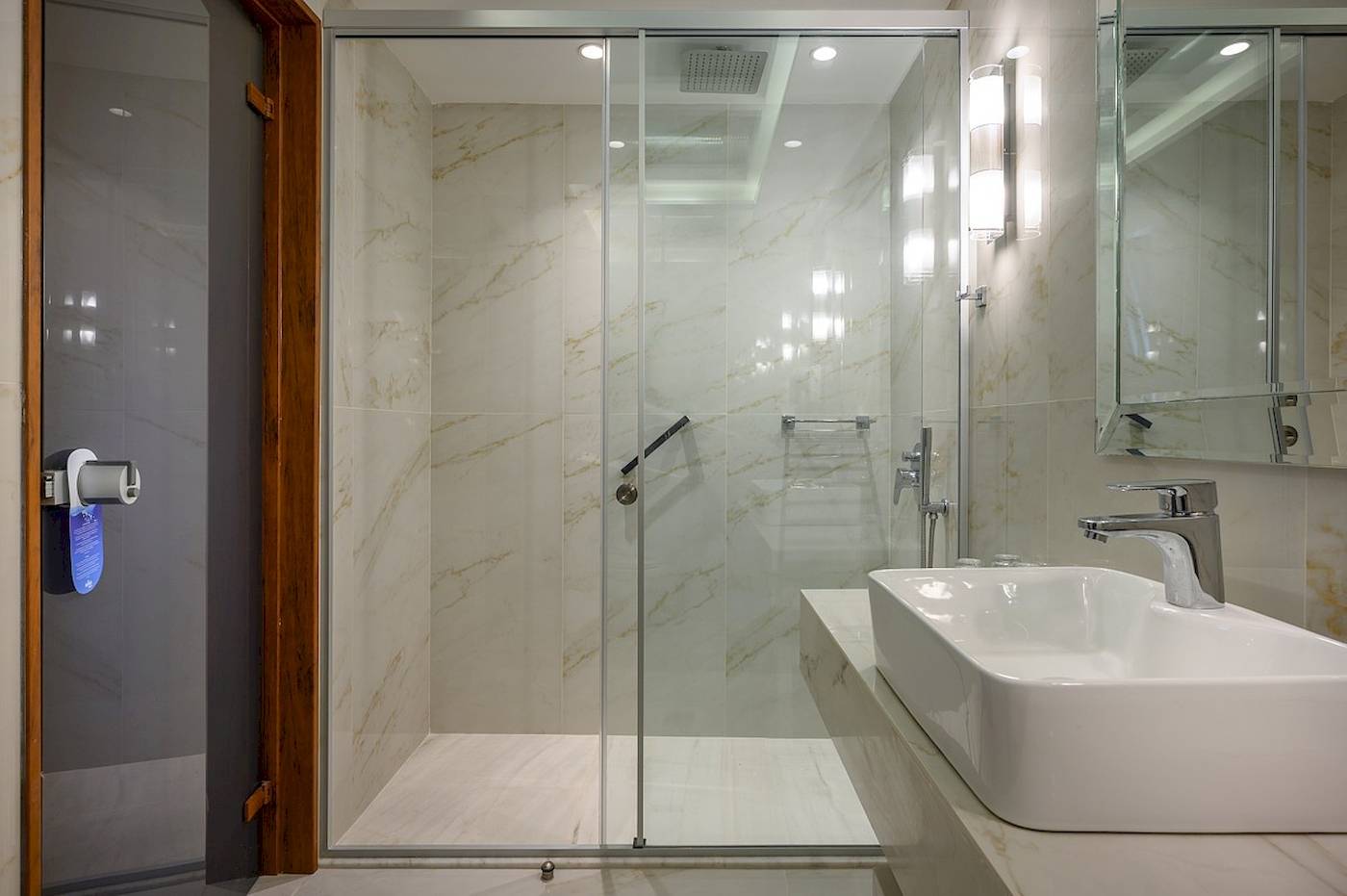 Badezimmer im Vantaris Palace mit einer Glasdusche und einem Waschbecken.