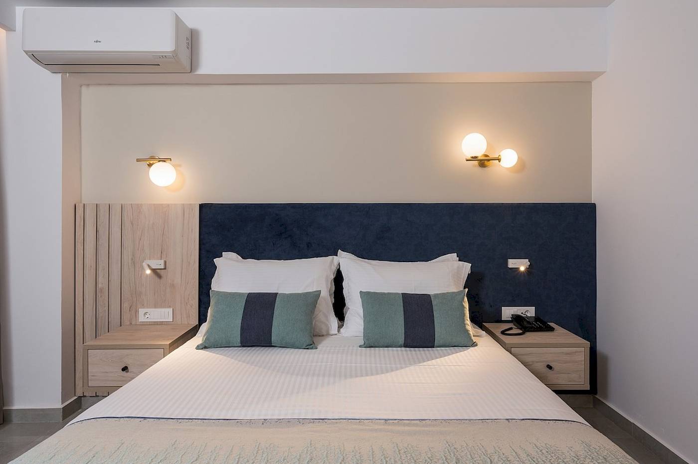 Hotelzimmer im Vantaris Palace mit Bett, Kopfteil, Nachttischen und Klimaanlage