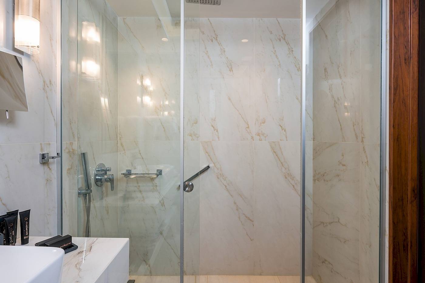 Vantaris Palace Badezimmer mit einer großen Glasdusche und Marmorwänden.