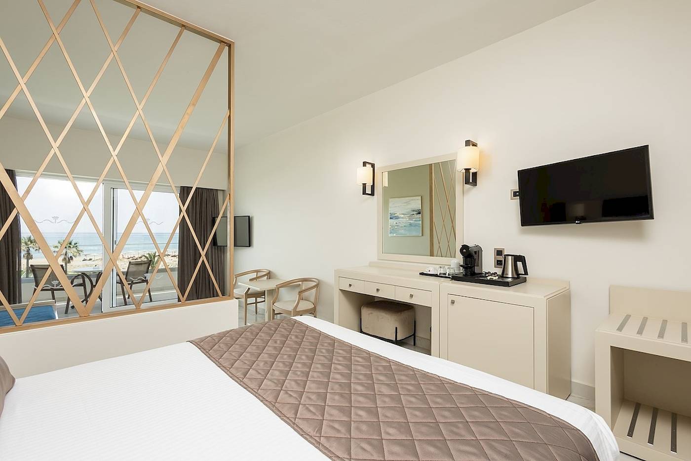 Hotelzimmer mit Meerblick im Vantaris Palace mit einem großen Bett, einem Schreibtisch und einem Fernseher an der Wand.