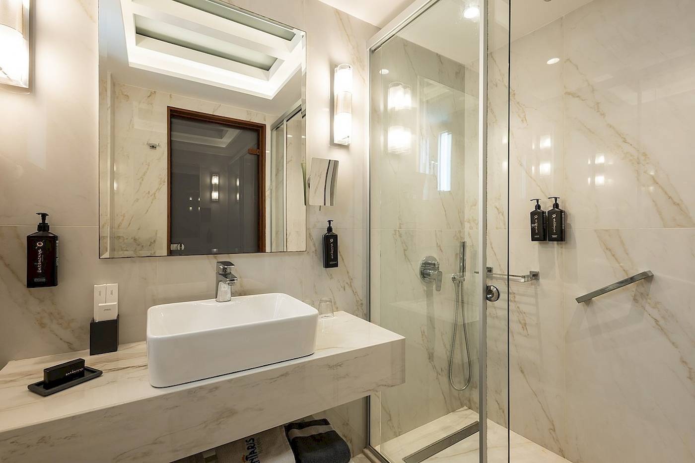 Badezimmer im Vantaris Palace Hotel mit weißer Marmorwand und Dusche
