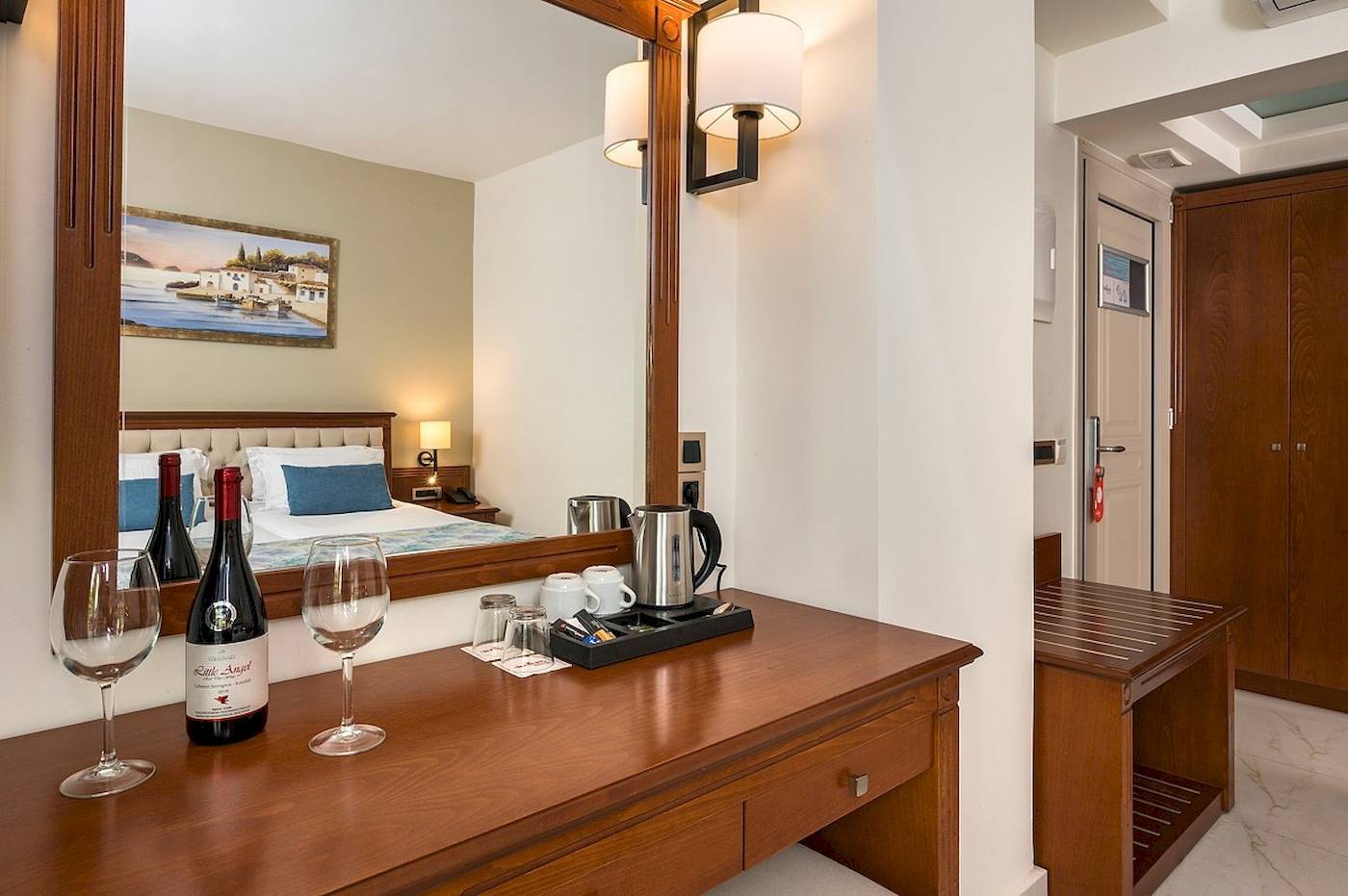 Zimmer im Vantaris Palace Hotel mit Bett, Weinflasche und Gläsern auf einem Schreibtisch.