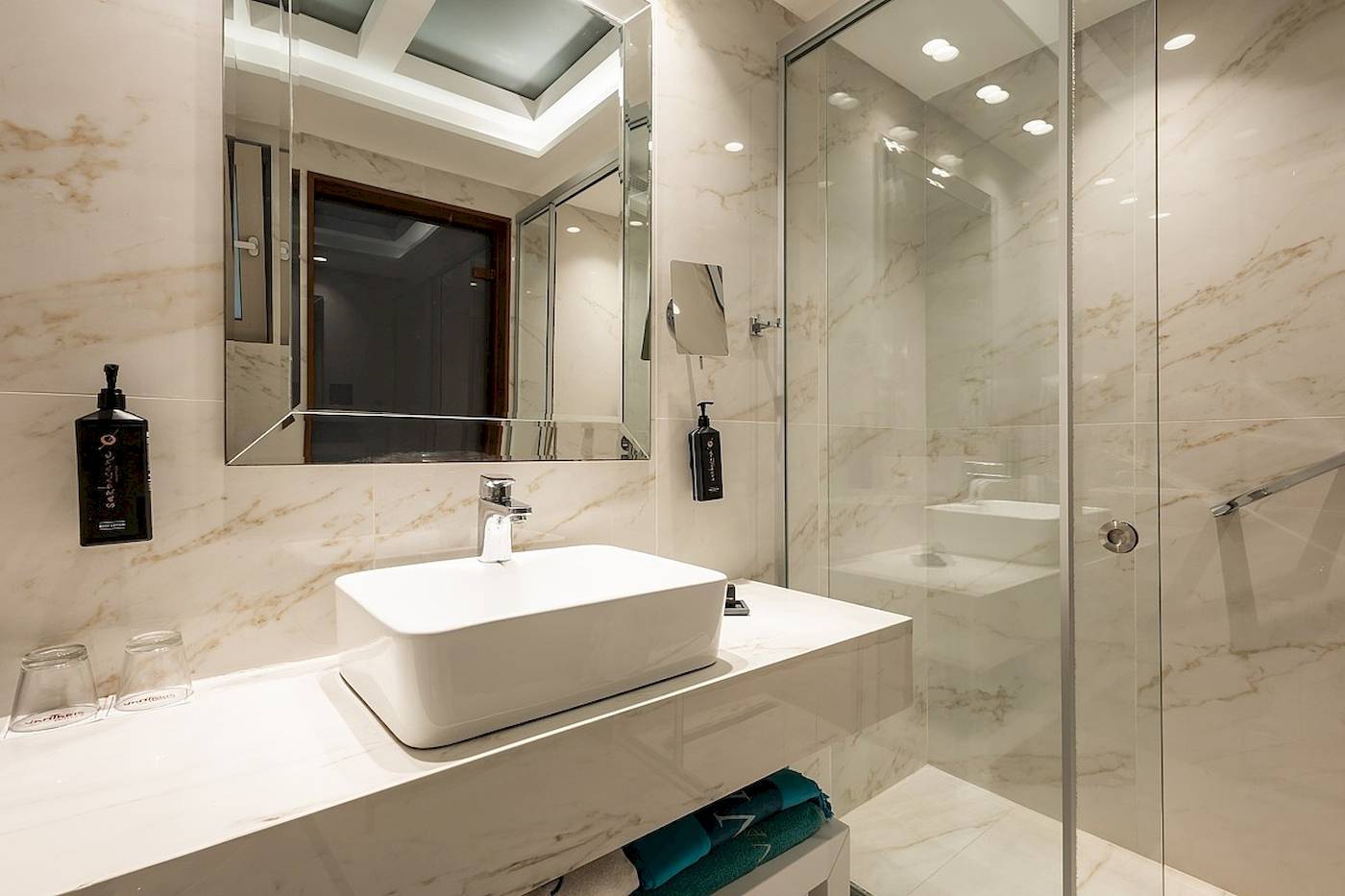Das Badezimmer im Vantaris Palace mit weißem Waschbecken und Spiegeln.