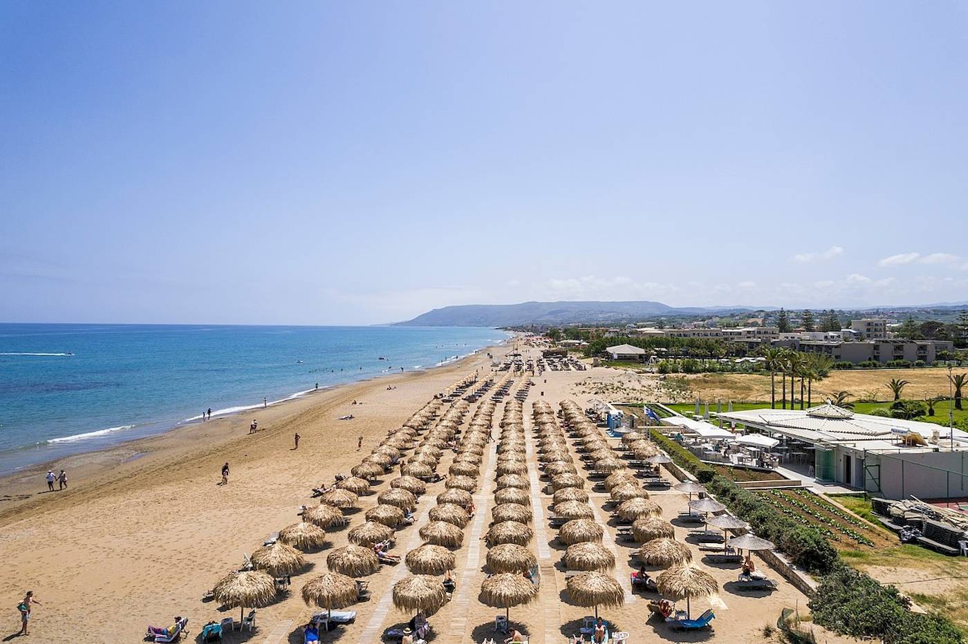 Luftaufnahme des Vantaris Palace Strandes mit vielen Sonnenschirmen und Gästen.
