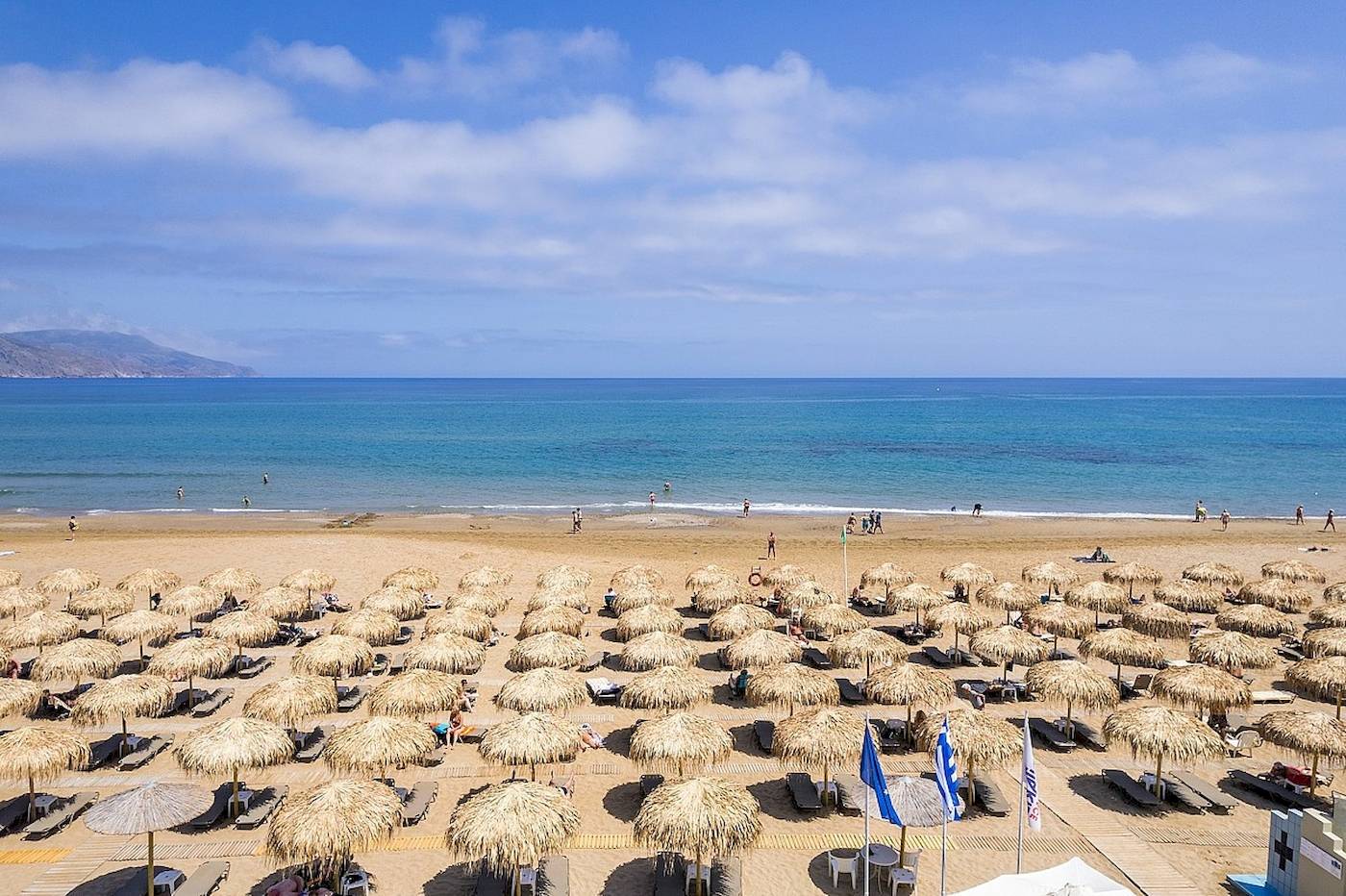 Luftaufnahme des Vantaris Palace Strandes mit vielen Sonnenschirmen und Strandliegen.