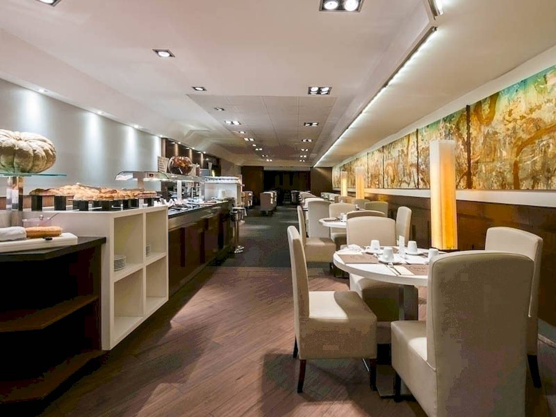 Frühstücksraum im Colonial Barcelona Hotel mit Tischen, Stühlen und Buffet.