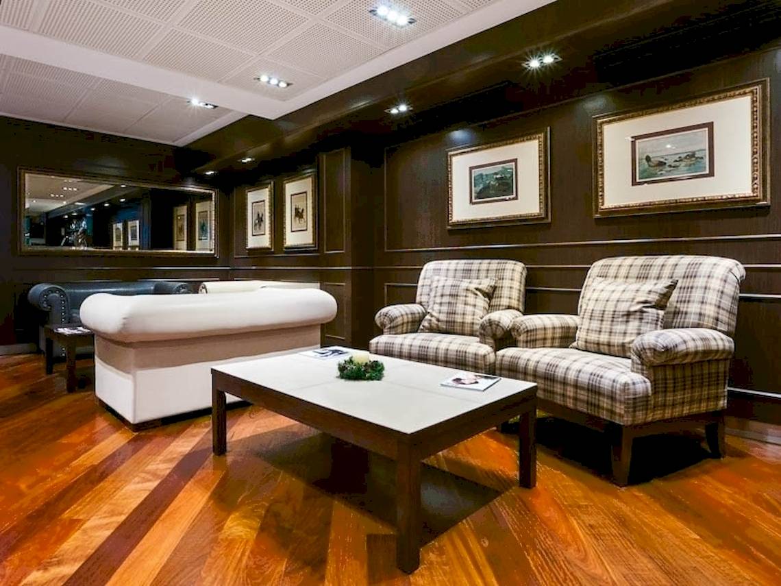 Lobby im Colonial Barcelona Hotel mit weißen Sofas, einem Tisch und Gemälden an der Wand.