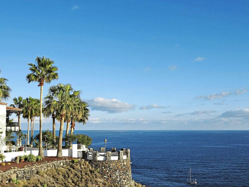 Meerblick von einem Hotel mit Garten und Palmen, Segelboot im Hintergrund