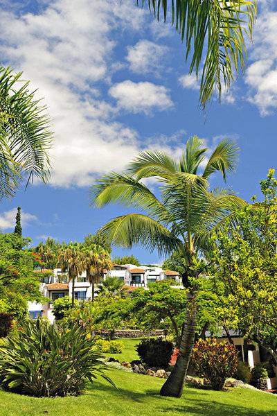 Gartenansicht des Jardin Tecina Hotels mit Palmen und Gebäuden im Hintergrund