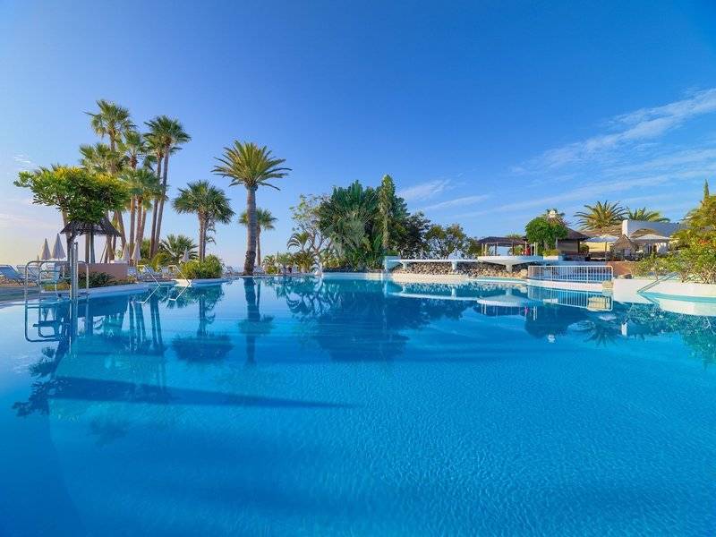 Pool im Jardin Tecina Hotel mit blauem Wasser und umliegenden Palmen