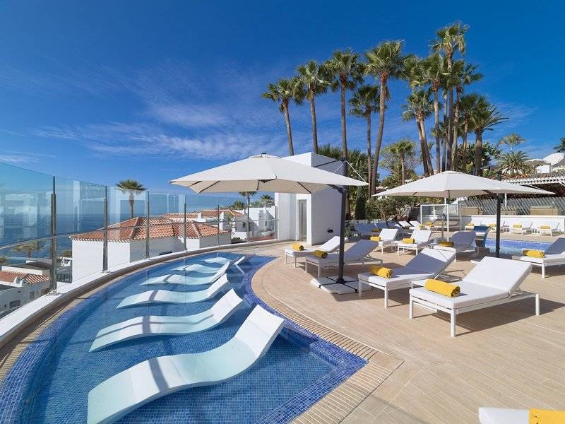 Pool-Terrasse im Jardin Tecina Hotel mit weißen Sonnenliegen und großen Sonnenschirmen