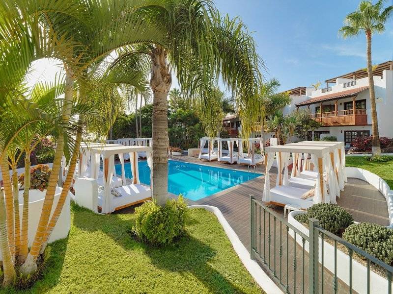Außenpoolbereich des Jardin Tecina Hotels mit weißen Sonnenbetten und Palmen