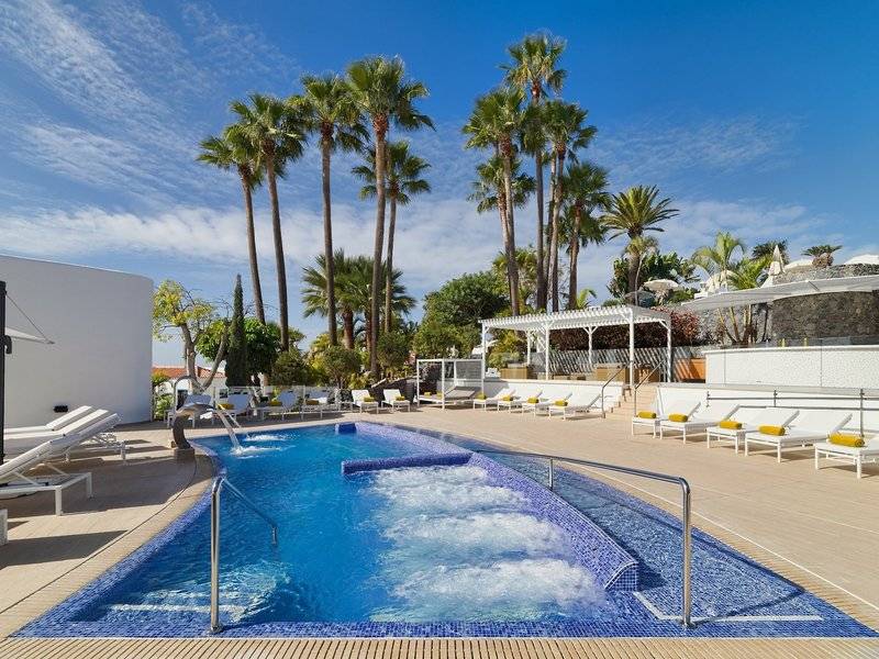 Poolbereich des Jardin Tecina Hotels mit vielen Liegestühlen und Palmen