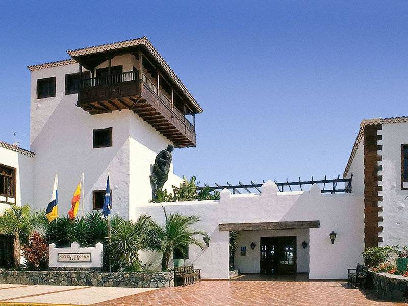 Das Jardin Tecina Hotel mit einer Statue, Flaggen und einem gepflasterten Eingangsbereich.