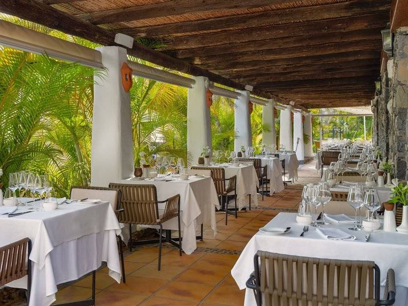 Innenansicht des Restaurants des Jardin Tecina Hotels mit gedeckten Tischen und Stühlen unter einer Holzdecke.