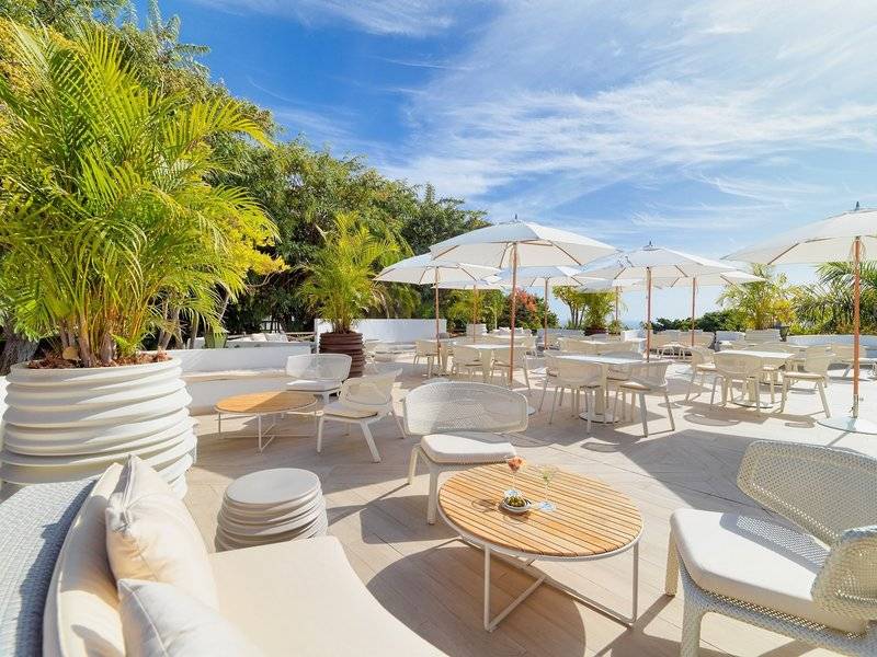 Terrasse des Jardin Tecina Hotels mit Tischen unter Schirmen und Pflanzen