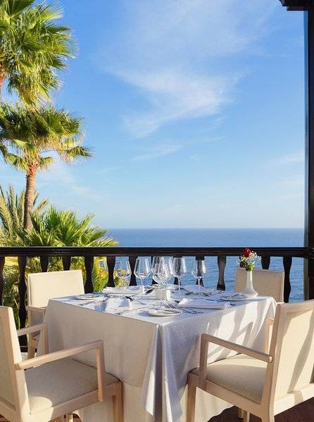 Gartentisch mit Meerblick im Hotel Jardin Tecina, serviert mit Wein und Blumen.