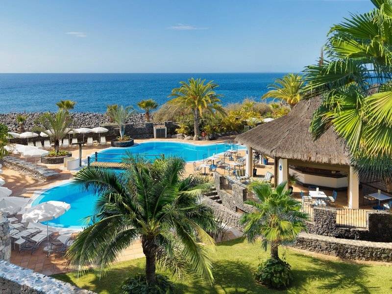 Oberansicht des Jardin Tecina Hotels mit Außenpool, Sonnenliegen und Blick auf das Meer.