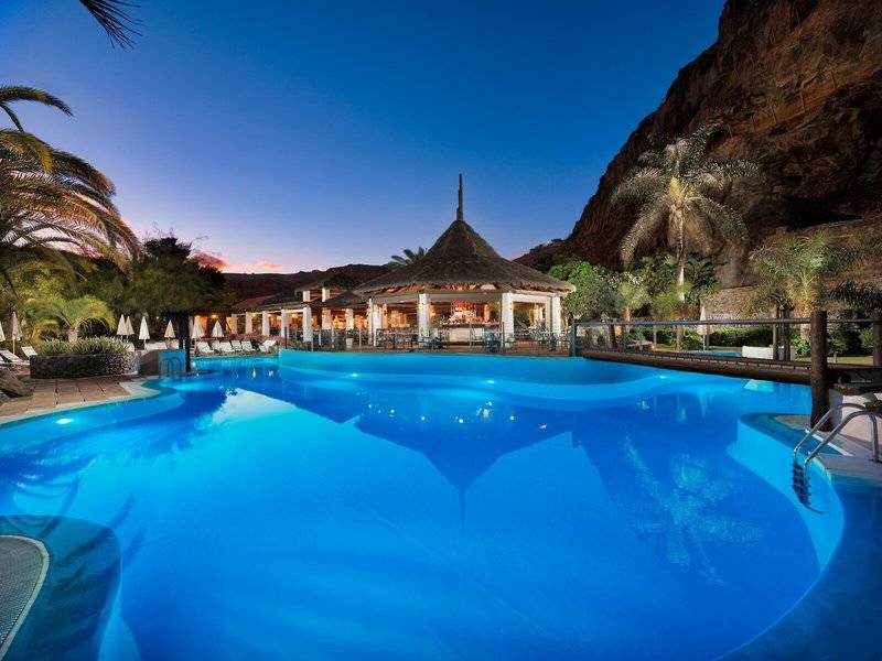 Außenpool des Jardin Tecina Hotels bei Abendbeleuchtung mit Blick auf die Bar und die Liegen