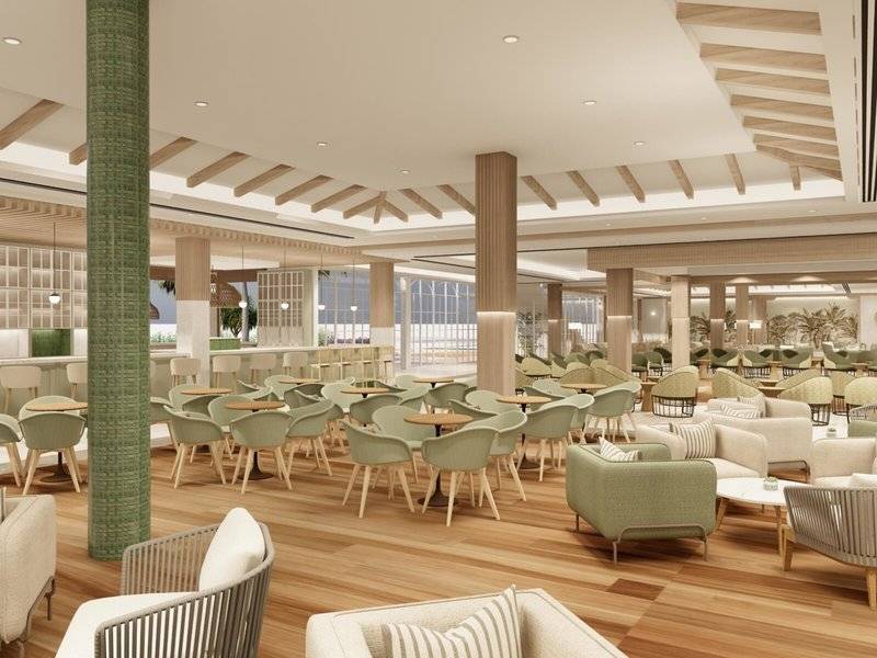 Innenbereich des Jardin Tecina Hotels mit vielen grünen Stühlen und Tischen, Holzboden und hohen Decken.