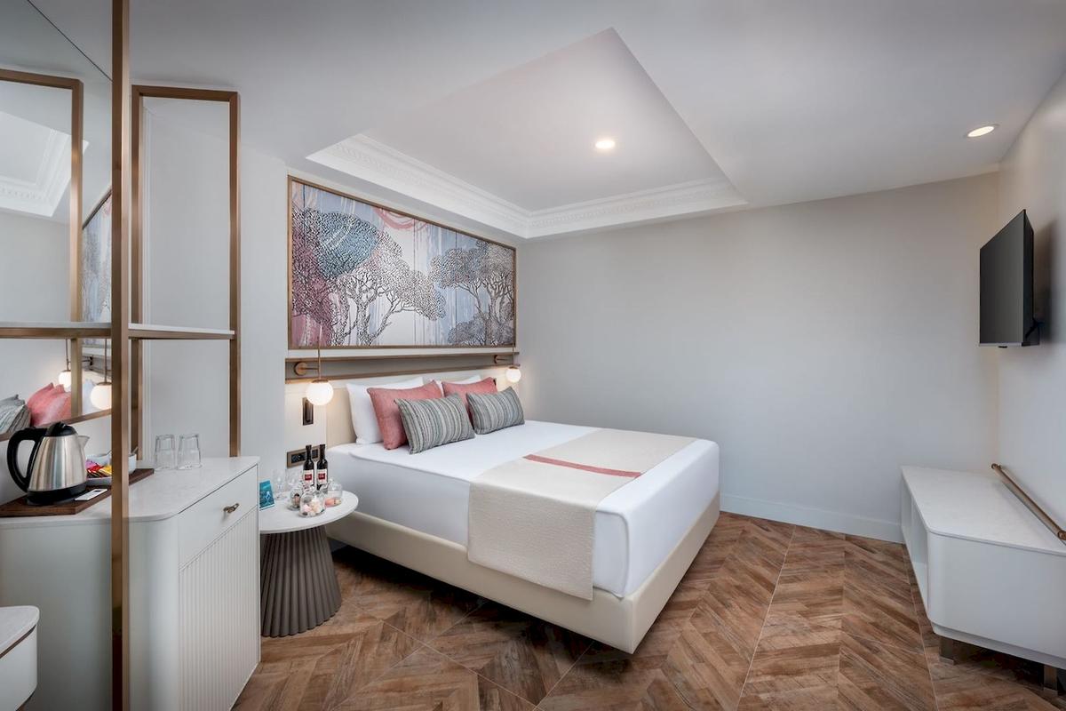 Das elegante Zimmer im Delphin Palace Hotel mit großem Bett, Kunstwerk an der Wand und modernen Möbeln.