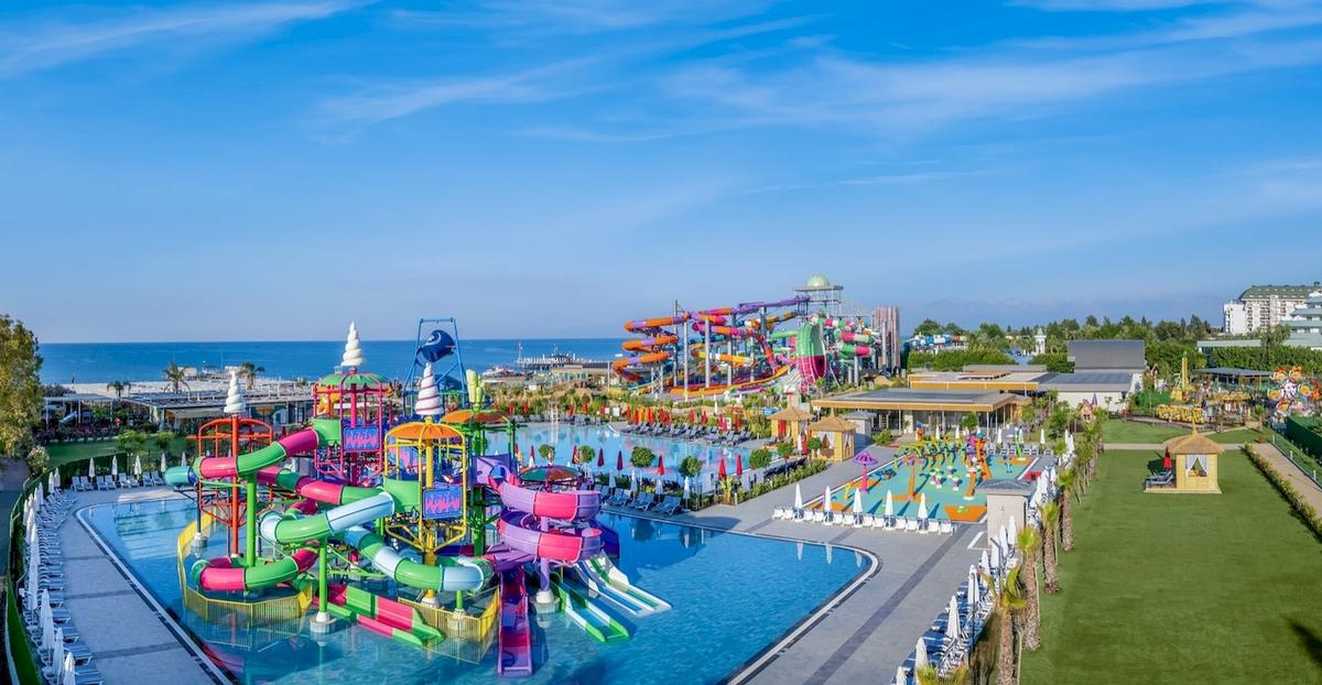 Außenansicht des Delphin Palace Wasserparks mit bunten Wasserrutschen und einem großen Pool.
