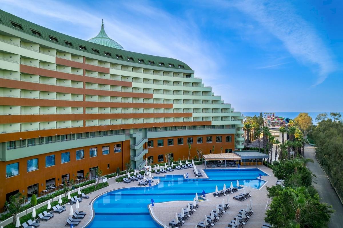 Außenansicht des Delphin Palace Hotels mit Swimmingpool und Sonnenliegen.