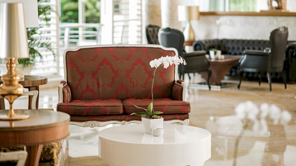 Hotellobby des JOIA Bávaro by Iberostar mit rotem Sofa, weißer Tisch und weißen Orchideen