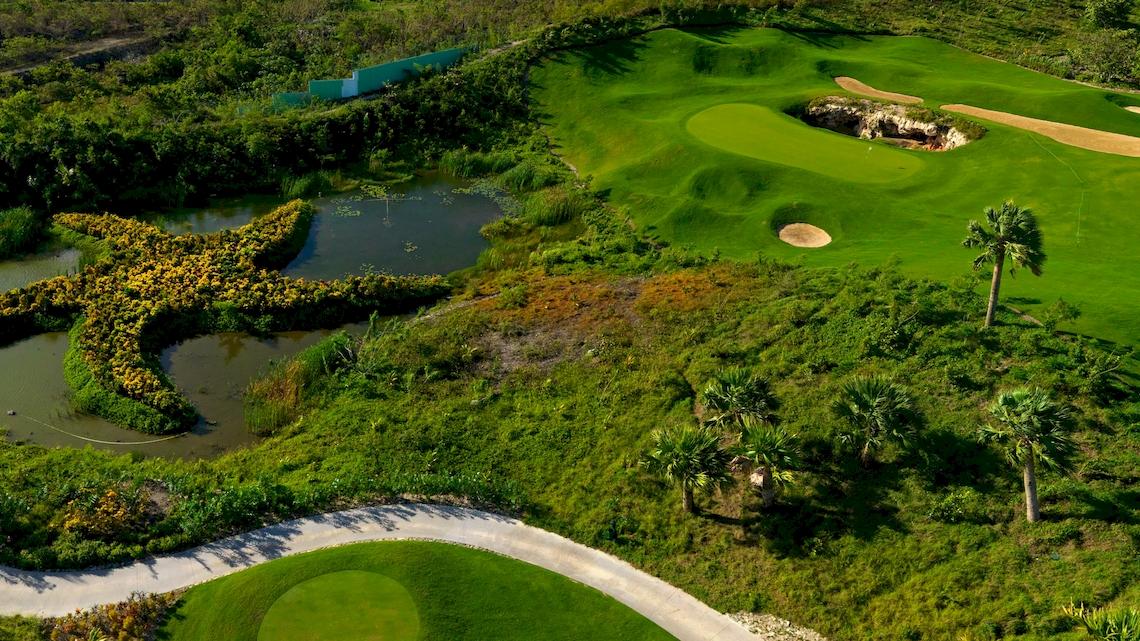 Golfplatz mit sternförmigem Wasserlauf und Palmen, gesehen von oben.