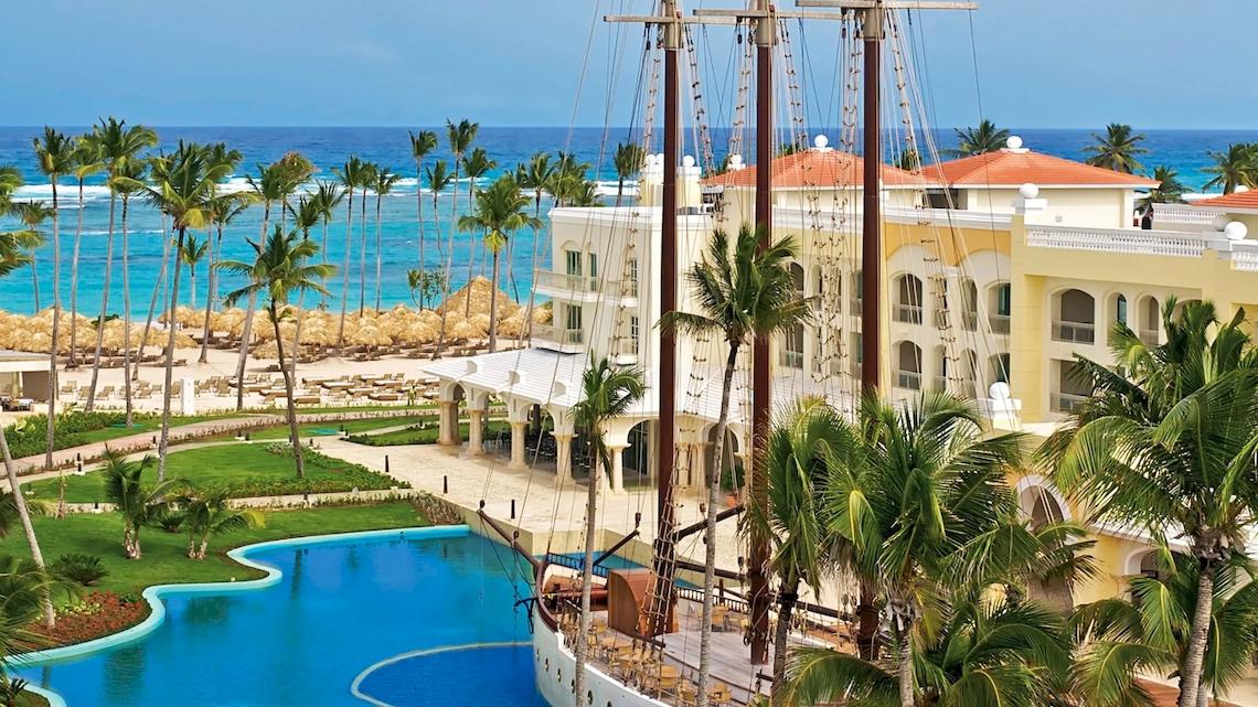 Außenansicht des JOIA Bávaro by Iberostar Hotels mit Pool und Segelboot.