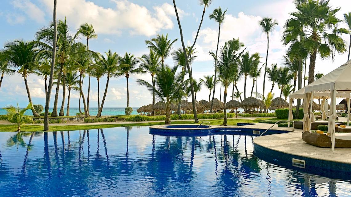 Außenpool des JOIA Bávaro by Iberostar Hotels mit Blick auf das Meer und Palmen