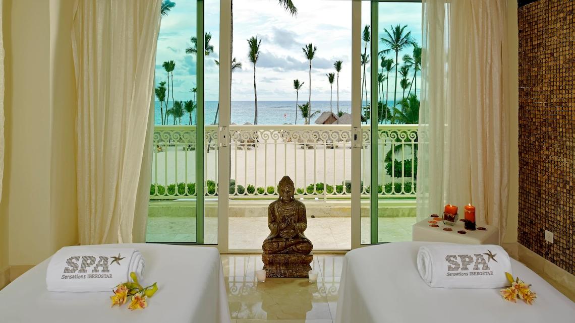Spa-Behandlungsraum im Hotel JOIA Bávaro by Iberostar mit Blick auf das Meer und Palmen.