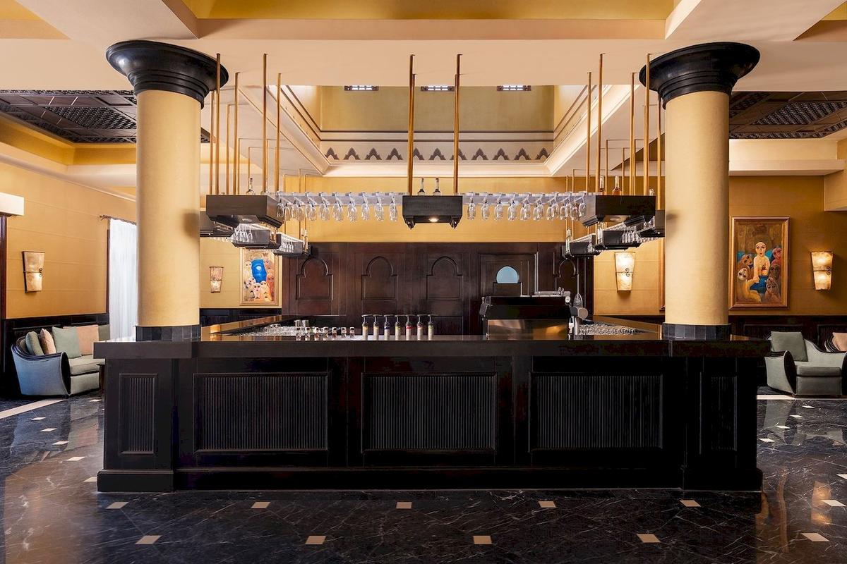 Innenbereich der Bar im Jaz Lamaya Resort Hotel mit schwarzen Theken und hohen Säulen.