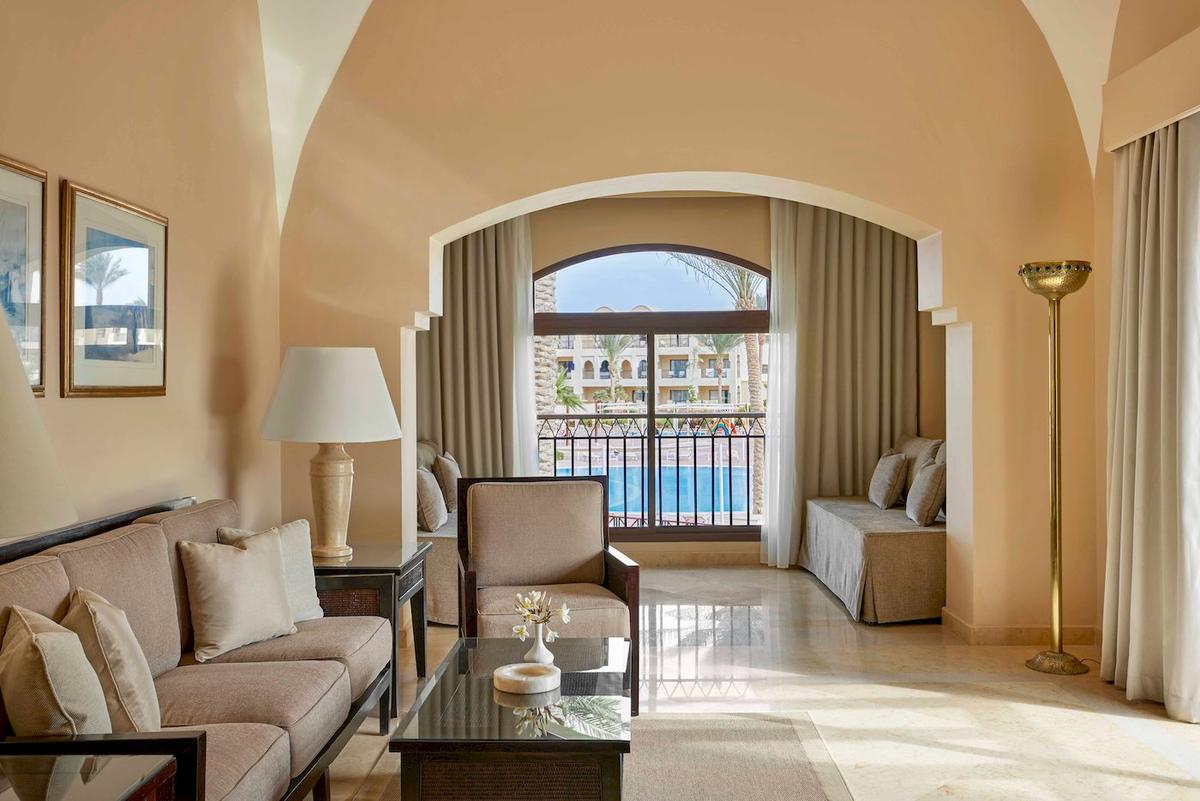 Wohnzimmer des Jaz Lamaya Resorts mit Sofa, Tisch, Lampe und Terrassenfenster mit Poolblick