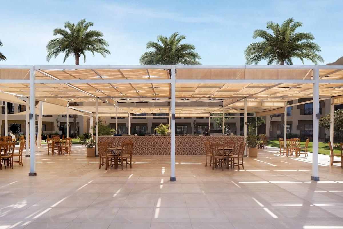Außenterrasse des Jaz Lamaya Resorts mit Tischen, Stühlen und Sonnenschirmen.