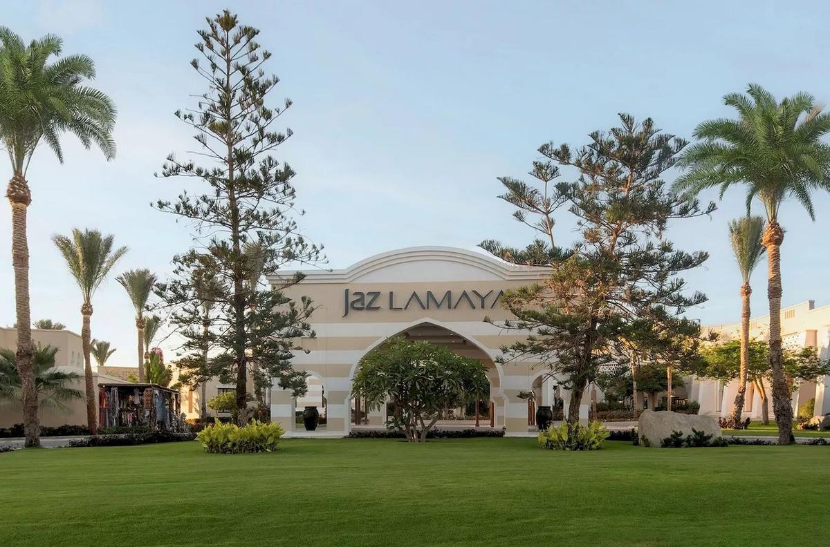 Eingang des Jaz Lamaya Resorts mit Palmen und Rasen.