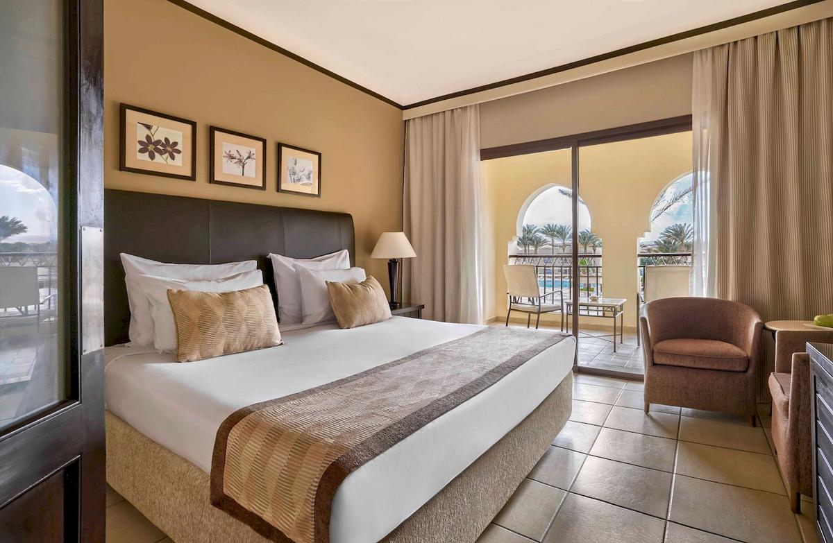 Hotelzimmer im Jaz Lamaya Resort mit bequemem Bett und gemütlichem Balkonzugang.