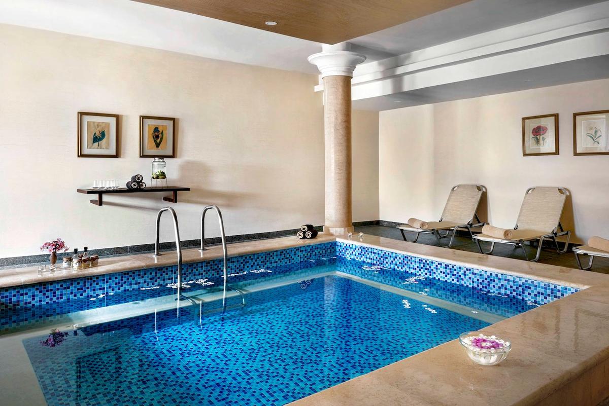 Ein Schwimmbad im Jaz Lamaya Resort mit blauen Fliesen und Liegestühlen.