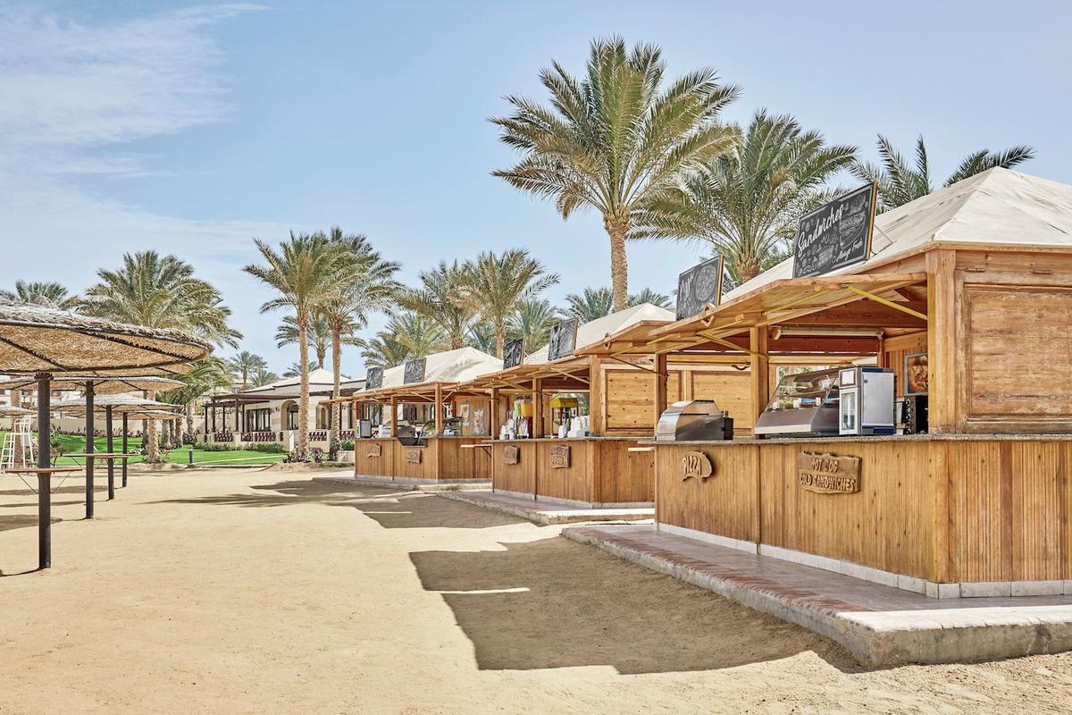Strandimbissbuden im Jaz Lamaya Resort mit Holzhütten und Palmen im Hintergrund.