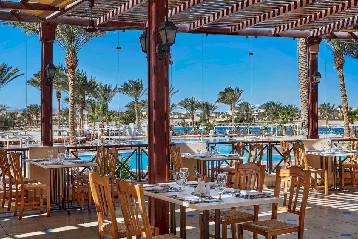Terrassenrestaurant im Jaz Lamaya Resort mit Tisch und Stuhl vor einem Pool.