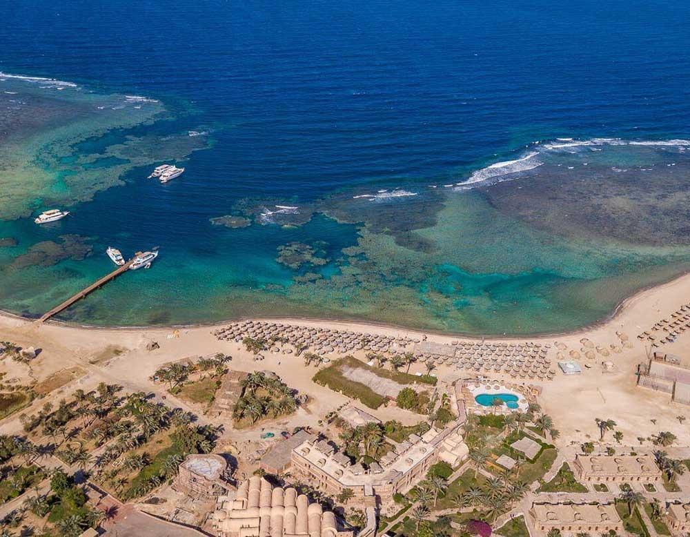 Luftaufnahme des Utopia Beach Clubs mit Strand, Gebäuden und Booten im Wasser.