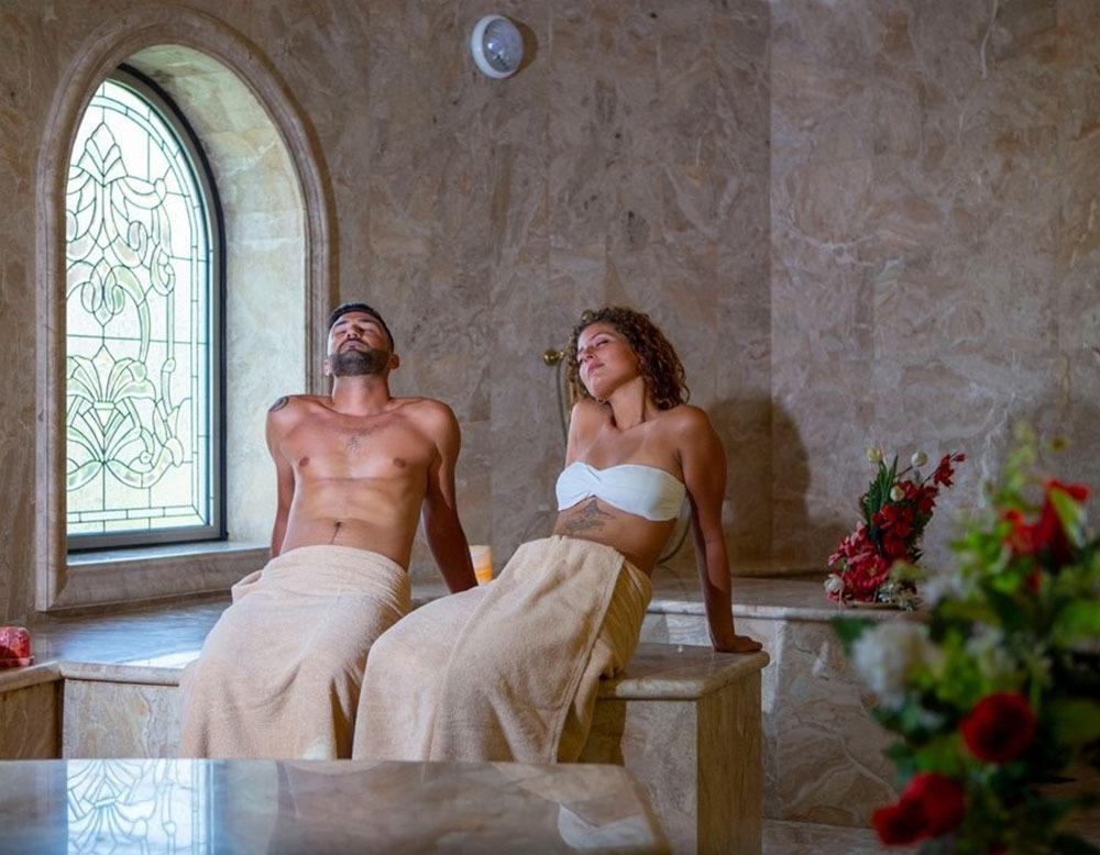 Ein Paar genießt die Sauna im Utopia Beach Club Hotel, mit Blumen im Vordergrund.
